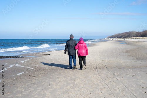 Fototapeta Naklejka Na Ścianę i Meble -  Elderly couple take a walk together at the Baltic Sea in winter