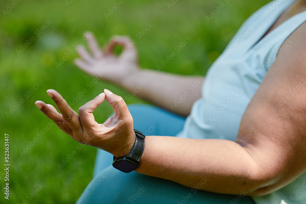 Close up of unrecognizable overweight woman doing yoga outdoors and meditating with focus on hands, copy space
