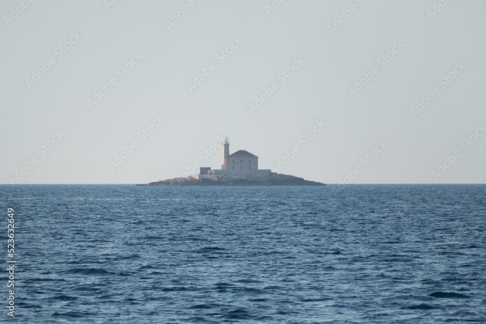 lighthouse at a small rocky island in sea