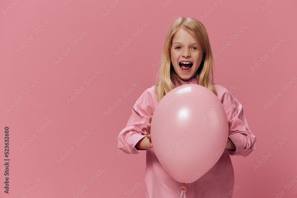 horizontal portrait of a girl in a pink shirt on a pink background with a pink balloon in her hands, screaming loudly looking at the camera horizontal portrait of a girl in a pink shirt on a pink background with a pink balloon in her hands, screaming loudly looking at the camera