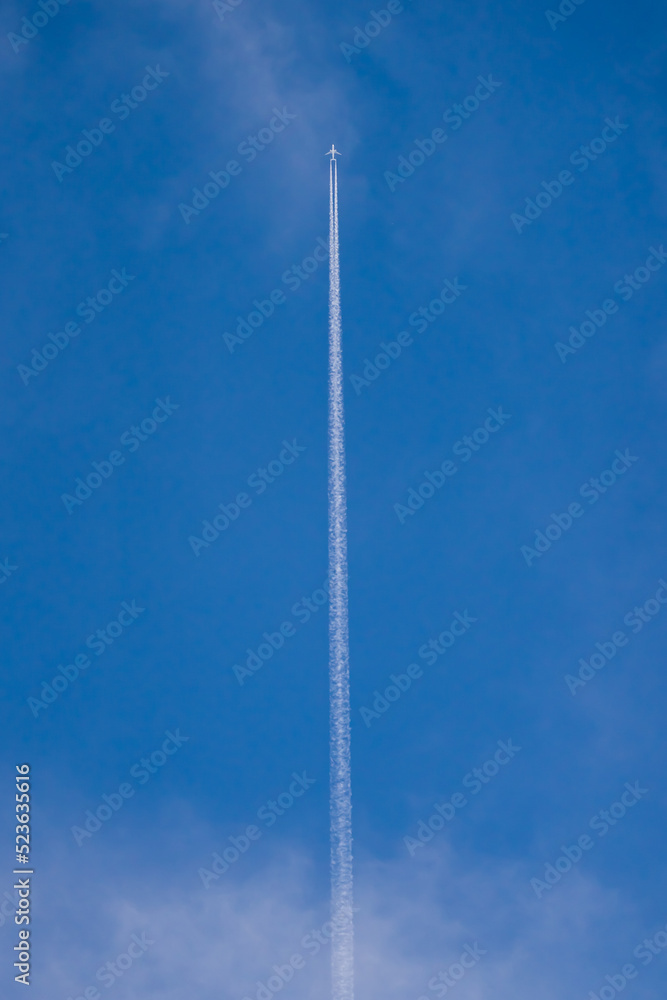 Long white trail of flying plane in blue sky Long white trail of flying plane in blue sky