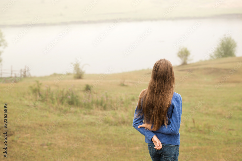 A young girl walks on a foggy morning by the lake