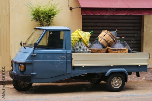 Un Ape, motorino italiano a tre ruote, caricato di damigiane per vino contadino, Italia photo