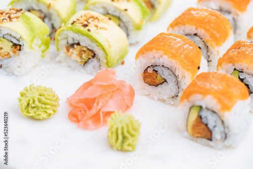 Sushi rolls on platter, bright background. Served with wasabi and ginger. Assorted Japanese sushi. Traditional food. 