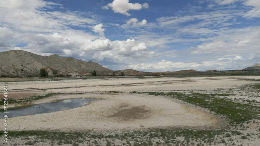Aerial-Flying low over dry lake bed as clouds tease but bring no relief to drought stricken reservoir as migrating water fowl search for the water where they historically stop over.