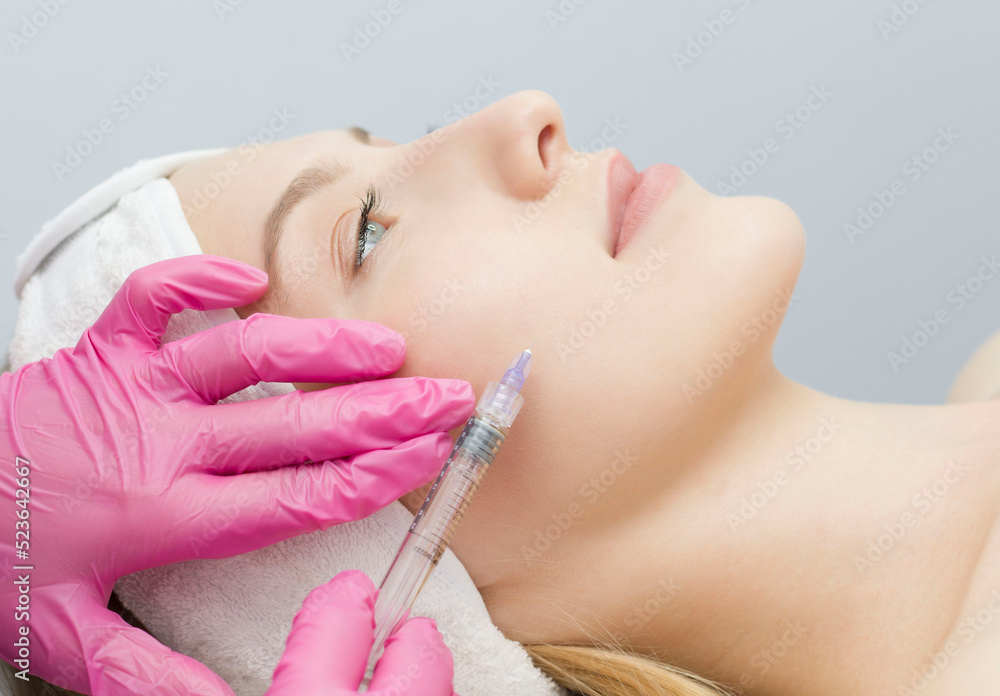 Injection in the face at the spa salon. The doctor's hands. Biorevitalization. Facial care with hyaluronic acid.