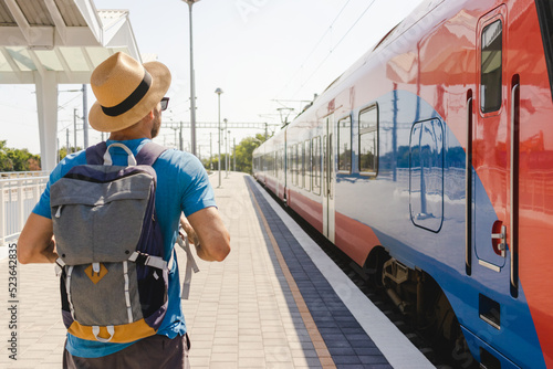 Man in hat with backpack traveling by train.