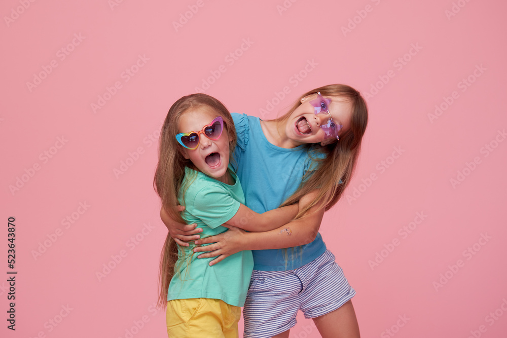 Cute adorable children having fun together with bright colorful t-shirts isolated on pink background Cute adorable children having fun together with bright colorful t-shirts isolated on pink background
