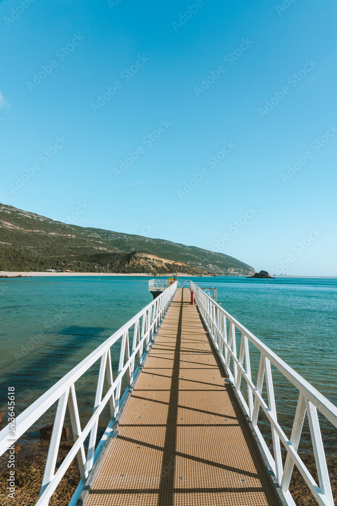 Fototapeta premium A small pier in a blue water beach in Arrabida National Park in Portugal