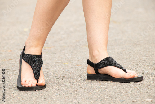 Women's feet in summer shoes on the road in the sun, women's feet in sandals