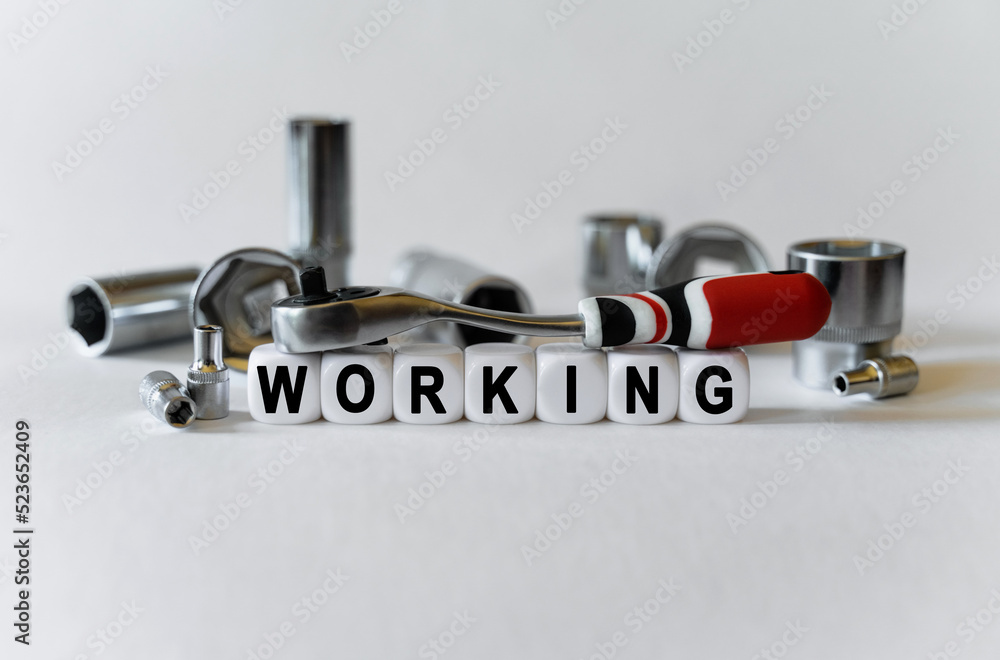 On a white background, a set with tools and white cubes with the inscription - working On a white background, a set with tools and white cubes with the inscription - working