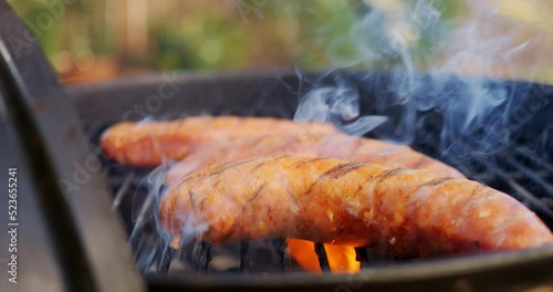 Slow motion video of sausage on BBQ dripping grease and flaming uop photo