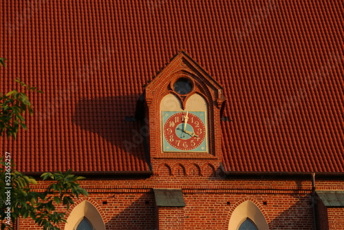 Zegar na gotyckim budynku z czerwonym dachem photo