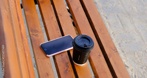 Coffee and a smartphone, a phone lie on a wooden bench, benches. Summer, rest, breakfast 