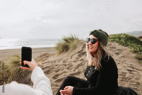 Two girls relaxing, sitting and taking theirself photos on the beach. Overcoming depression photo