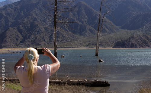 Blonde woman taking a picture in a beautiful scenery.