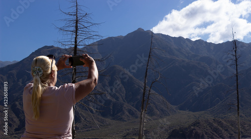 Blonde woman taking a picture in a beautiful scenery.