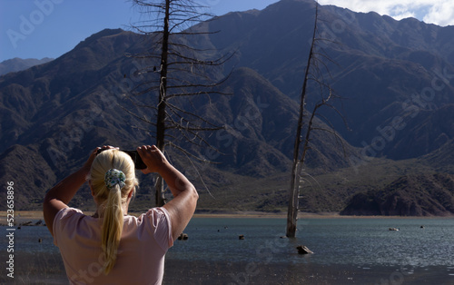 Blonde woman taking a picture in a beautiful scenery.