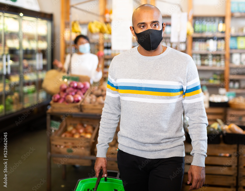 Portrait of Hispanic man in protective mask visiting grocery store during coronavirus pandemic..