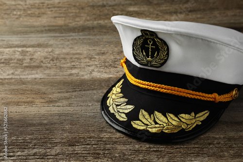 Peaked cap with accessories on wooden background, space for text