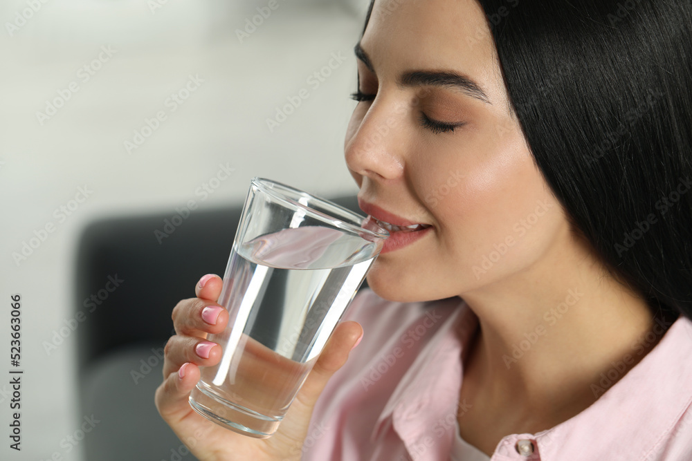 Young woman drinking water indoors, closeup. Refreshing drink Young woman drinking water indoors, closeup. Refreshing drink