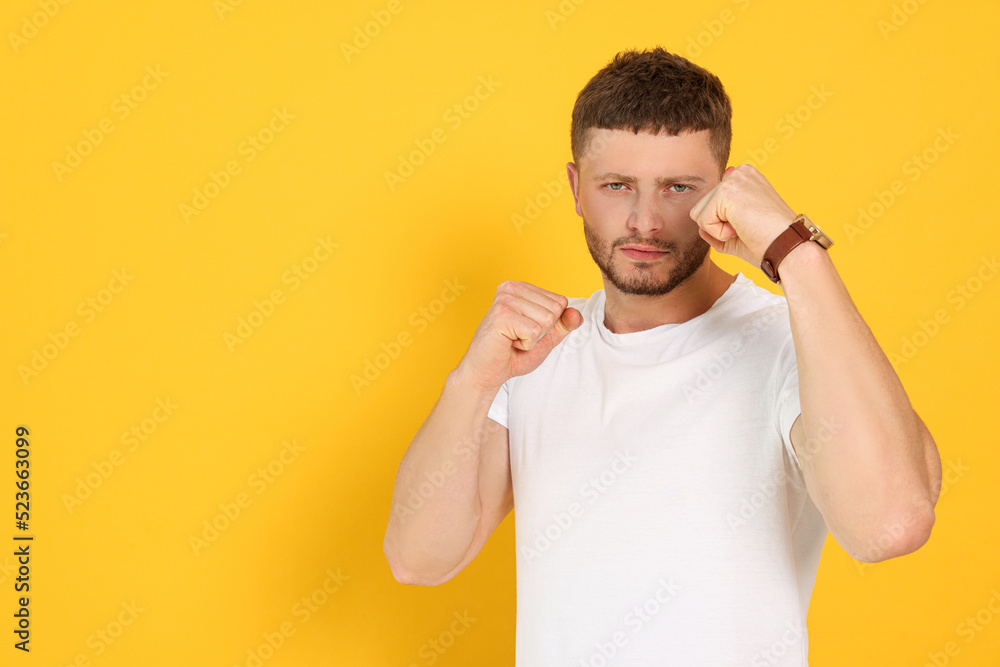Young man ready to fight on orange background, space for text Young man ready to fight on orange background, space for text