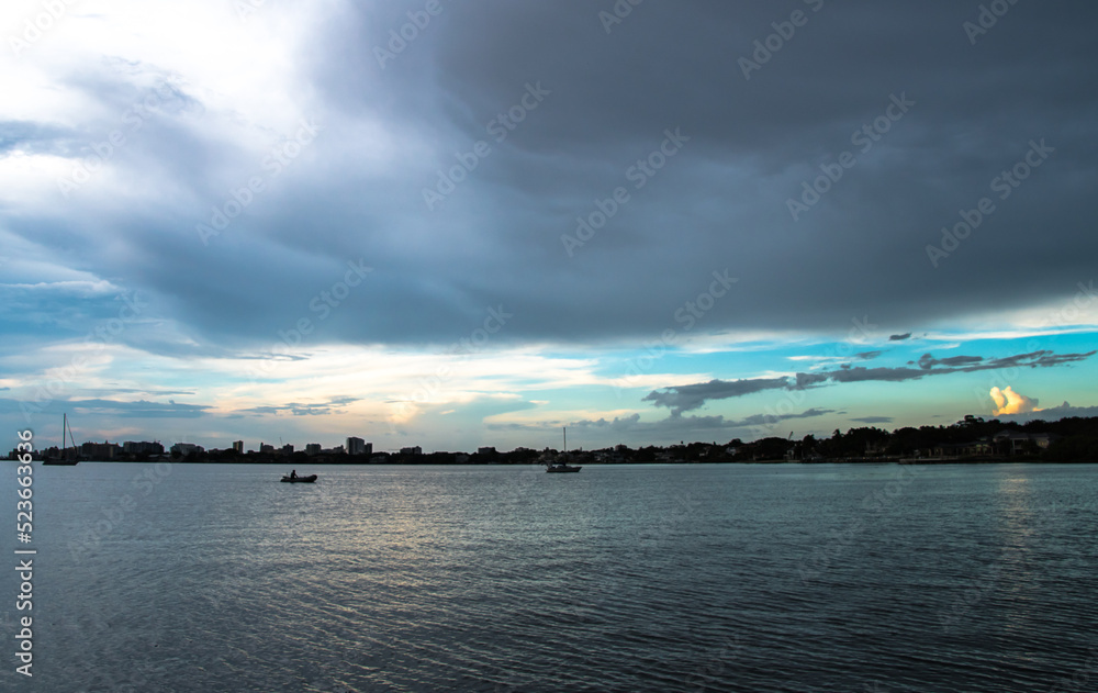 Dusk to Dawn over Sarasota Bay, Florida. Colorful stormy skies with Longboat Key and Sarasota downtown skyline in the distance. Light and colors.