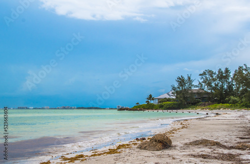 Siesta Key, Florida, popular travel tourist destination. Scene of the beach near Siesta Key Village at dusk as a storm appears in the distant sky. Cool blue turquois water along the rock studded shore photo