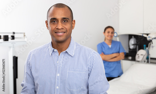 Portrait of happy Hispanic male patient after cosmetological procedure in modern aesthetic medicine office..