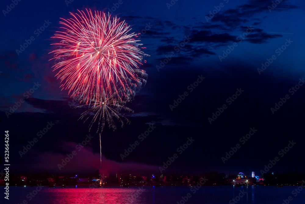 Fireworks celebration with reflections across the river with a town in the background Fireworks celebration with reflections across the river with a town in the background