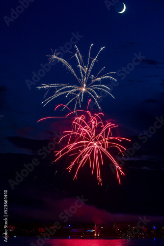 Fireworks celebration with reflections across the river with a town in the background