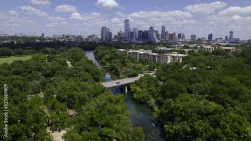 Aerial view over the Barton Creek, with the Austin city skyline in the background  - reverse, tilt, drone shot photo