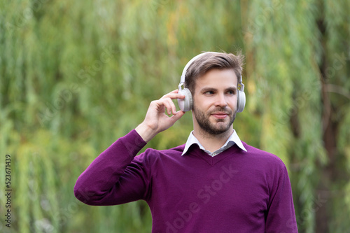 young handsome guy listen music in headphones outdoor