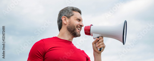 man advertiser in red shirt shout in loudspeaker on sky background