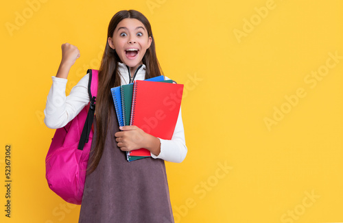 successful child with school backpack and workbook on yellow background