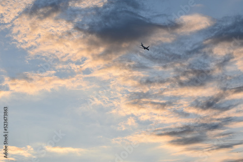 Avion volando en altura en el atardecer con nubes muy coloridas