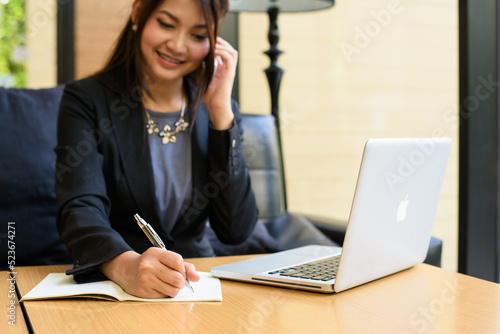 business woman phonecall and writing and using laptop