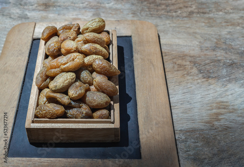 Terminalia bellerica or Terminalia chebula (Organic dry harad). Dried fruits in the wooden box. Ayurvedic herbal medicine. Copy space, Selective focus. photo