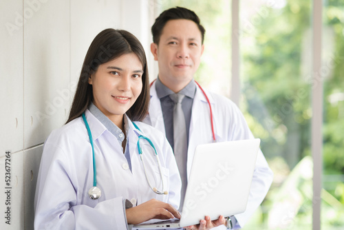 Group of Asian doctors team portrait standing with colleagues in background.