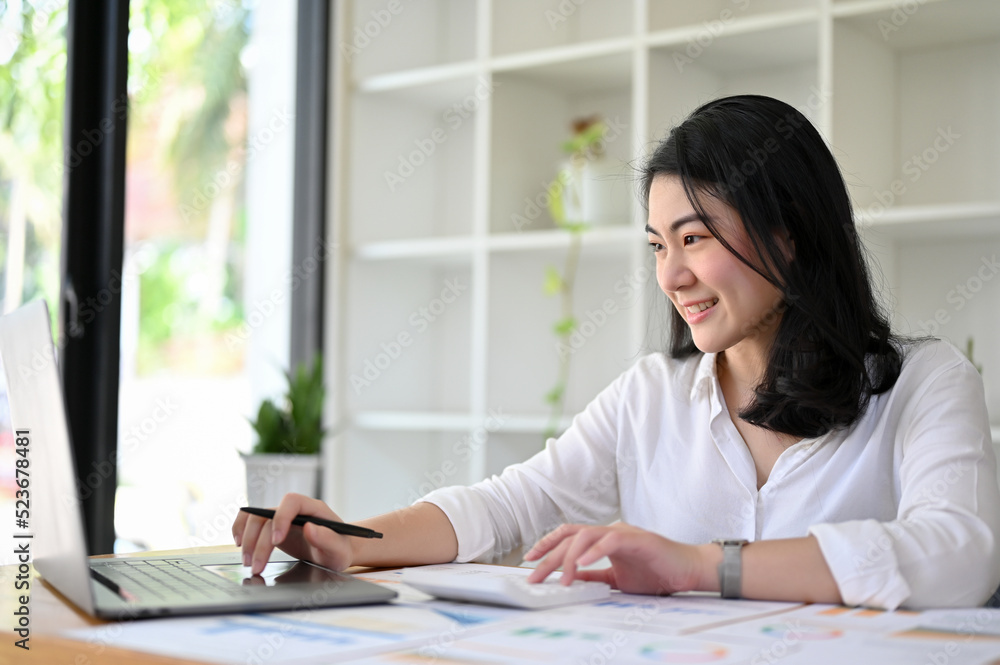 Charming Asian businesswoman or accountant using calculator and using laptop. Charming Asian businesswoman or accountant using calculator and using laptop.