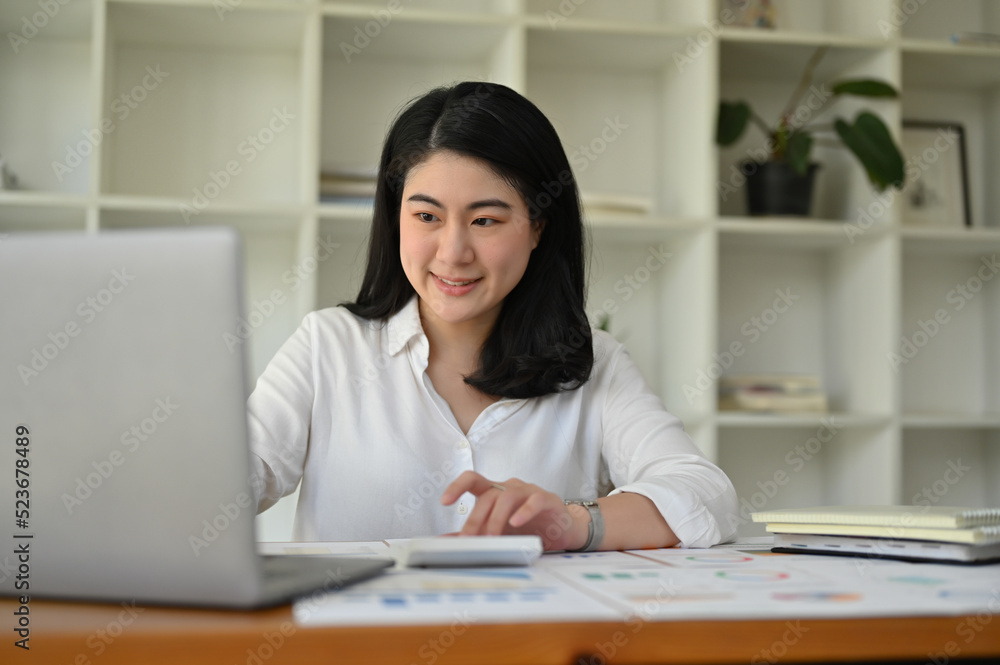 Successful Asian businesswoman at her office desk managing her tasks on her laptop. Successful Asian businesswoman at her office desk managing her tasks on her laptop.
