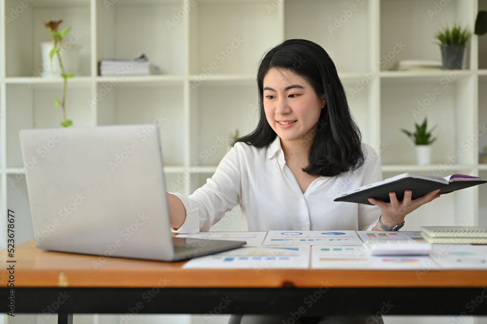 Beautiful Asian businesswoman working at her office desk, using laptop computer. Beautiful Asian businesswoman working at her office desk, using laptop computer.