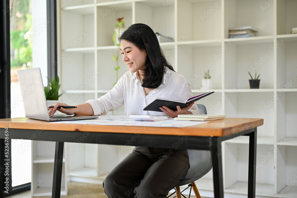 Attractive Asian businesswoman working at her office desk, using laptop Attractive Asian businesswoman working at her office desk, using laptop