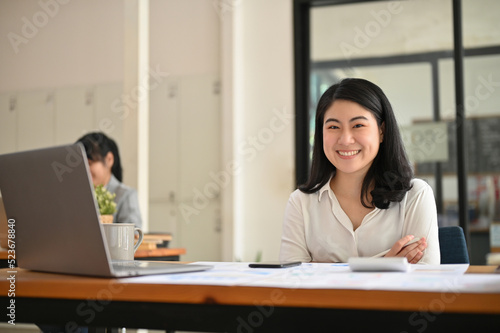 Attractive and happy young Asian businesswoman at her office desk.
