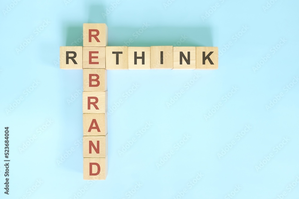 Rethink and rebrand business concept. Wooden blocks crossword puzzle flat lay in blue background.