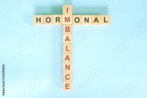 Hormonal imbalance concept. Wooden blocks crossword puzzle flat lay in blue background. photo