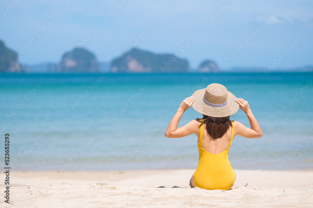 Woman tourist in yellow swimsuit and hat, happy traveler sunbathing at Paradise beach on Islands. destination, wanderlust, Asia Travel, tropical summer, vacation and holiday concept Woman tourist in yellow swimsuit and hat, happy traveler sunbathing at Paradise beach on Islands. destination, wanderlust, Asia Travel, tropical summer, vacation and holiday concept