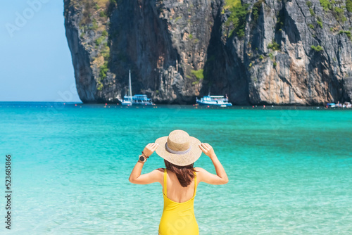 Woman tourist in yellow swimsuit and hat, happy traveller sunbathing at Maya Bay beach on Phi Phi island, Krabi, Thailand. landmark, destination Southeast Asia Travel, vacation and holiday concept © Jo Panuwat D