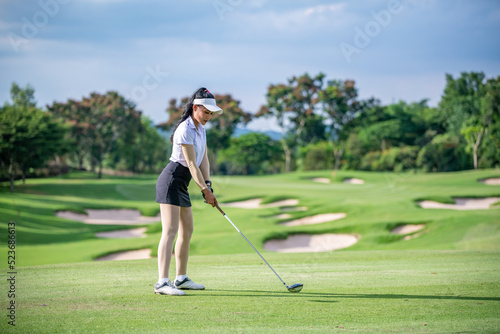 Professional woman golfer teeing golf in golf tournament competition at golf course for winner. 