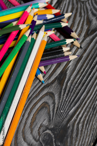 Colored pencils for drawing.  They lie on a table made of pine boards.